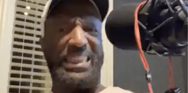 Man speaking into a microphone indoors.